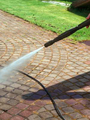 Cleaning street with high pressure power washer, washing stone garden paths Cleaning street with high pressure power washer, washing stone garden paths