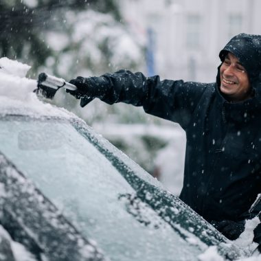 Middle aged man cleaning car from snow and ice Middle aged man cleaning car from snow and ice